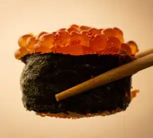 a close up of a sushi with chopsticks